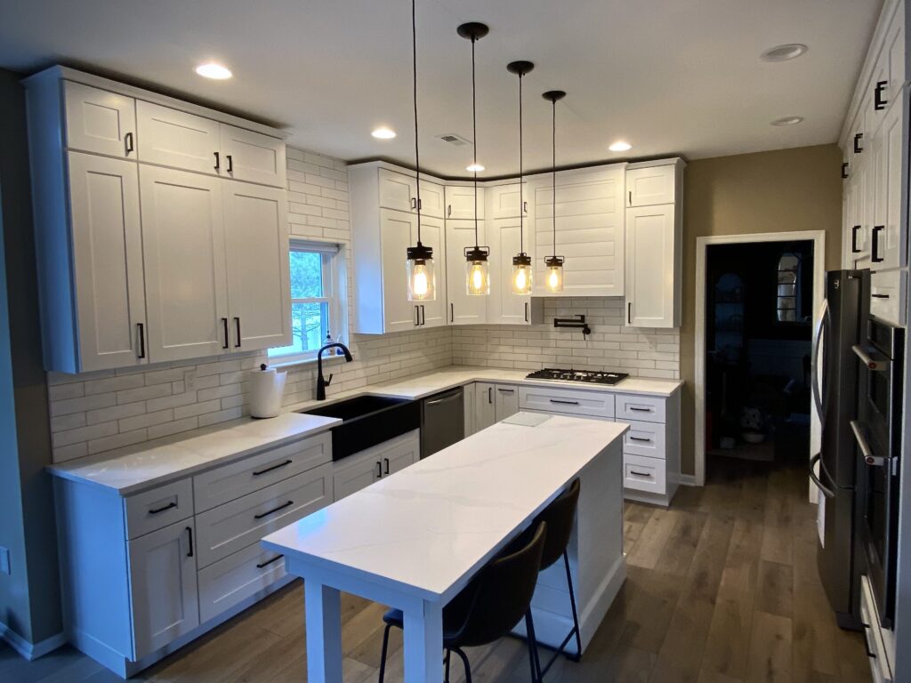 White kitchen with island and black appliances.