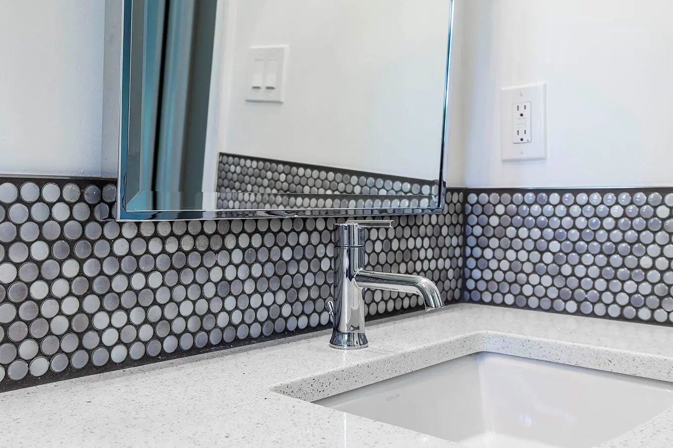 Bathroom sink with chrome faucet and tile.